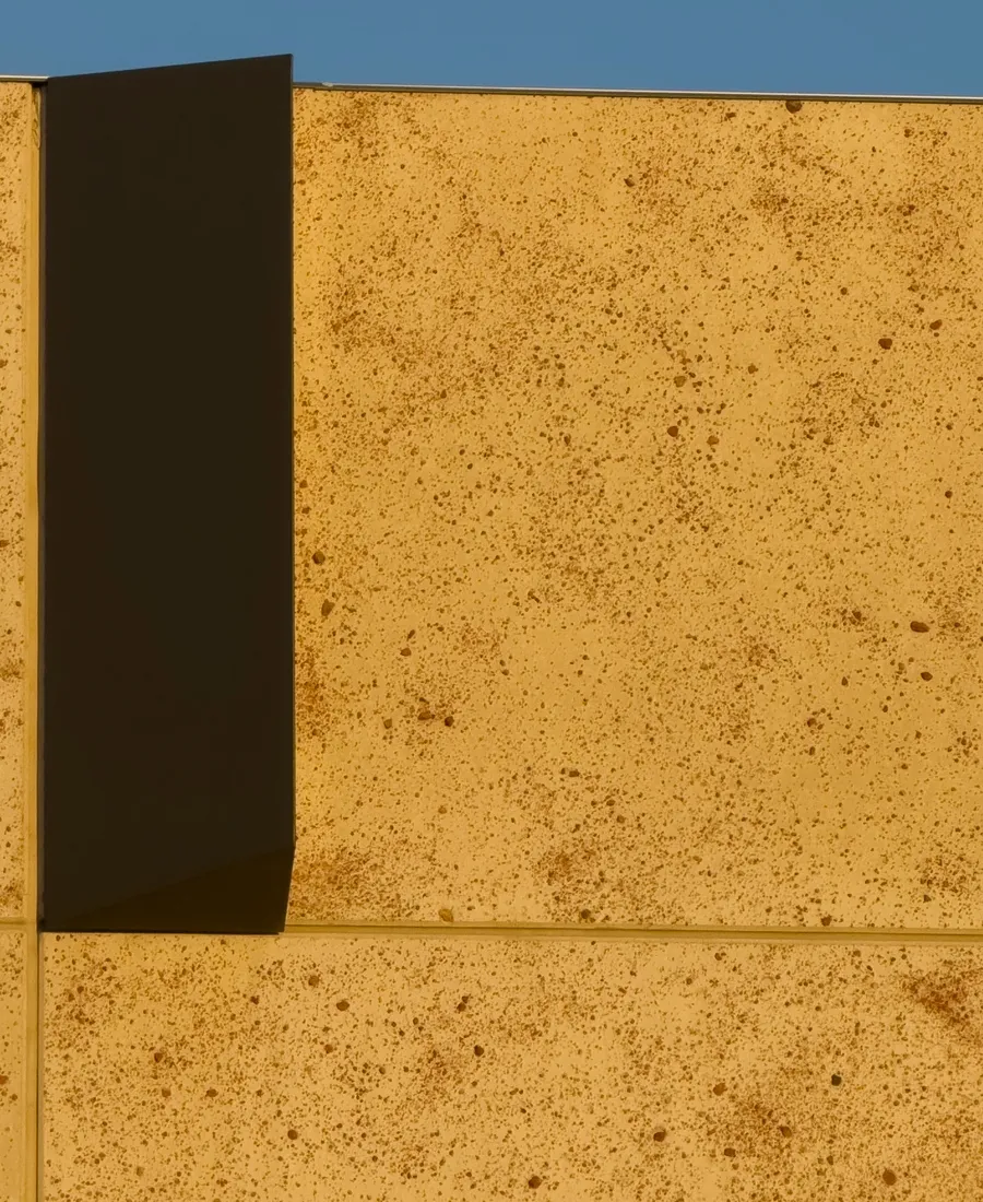 Sunlit warm stone architectural facade with shadow